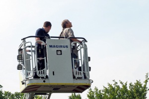 Zwei Personen im Korb einer Drehleiter eines Feuerwehrfahrzeugs.
